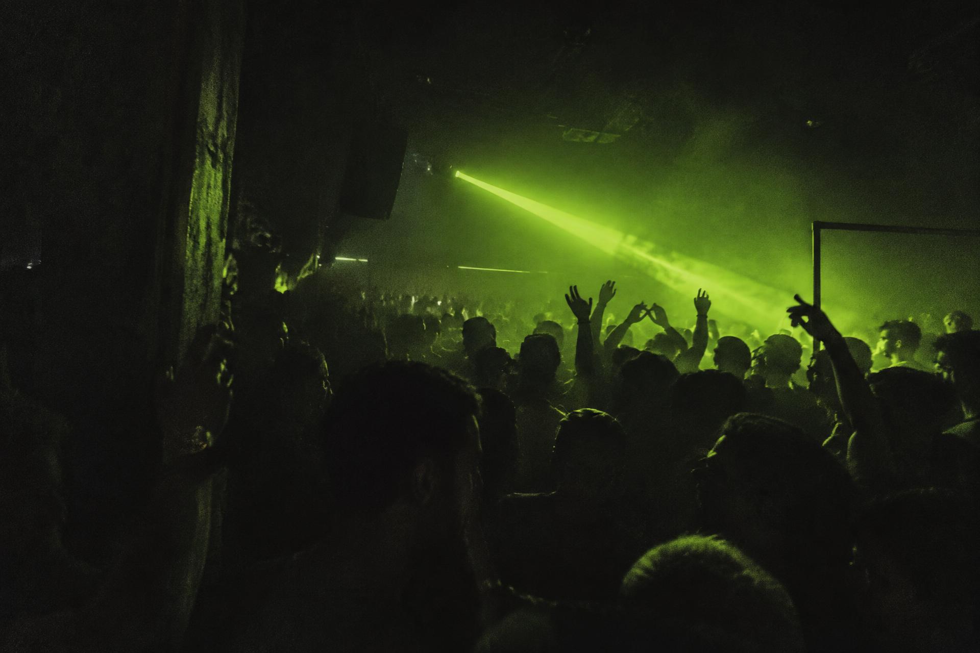 Dark nightclub dancefloor lit by a single green laser